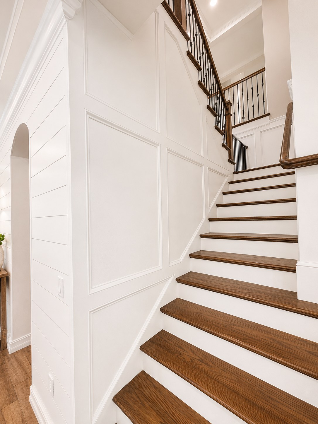 White picture-frame wainscoting and shiplap wall along a staircase