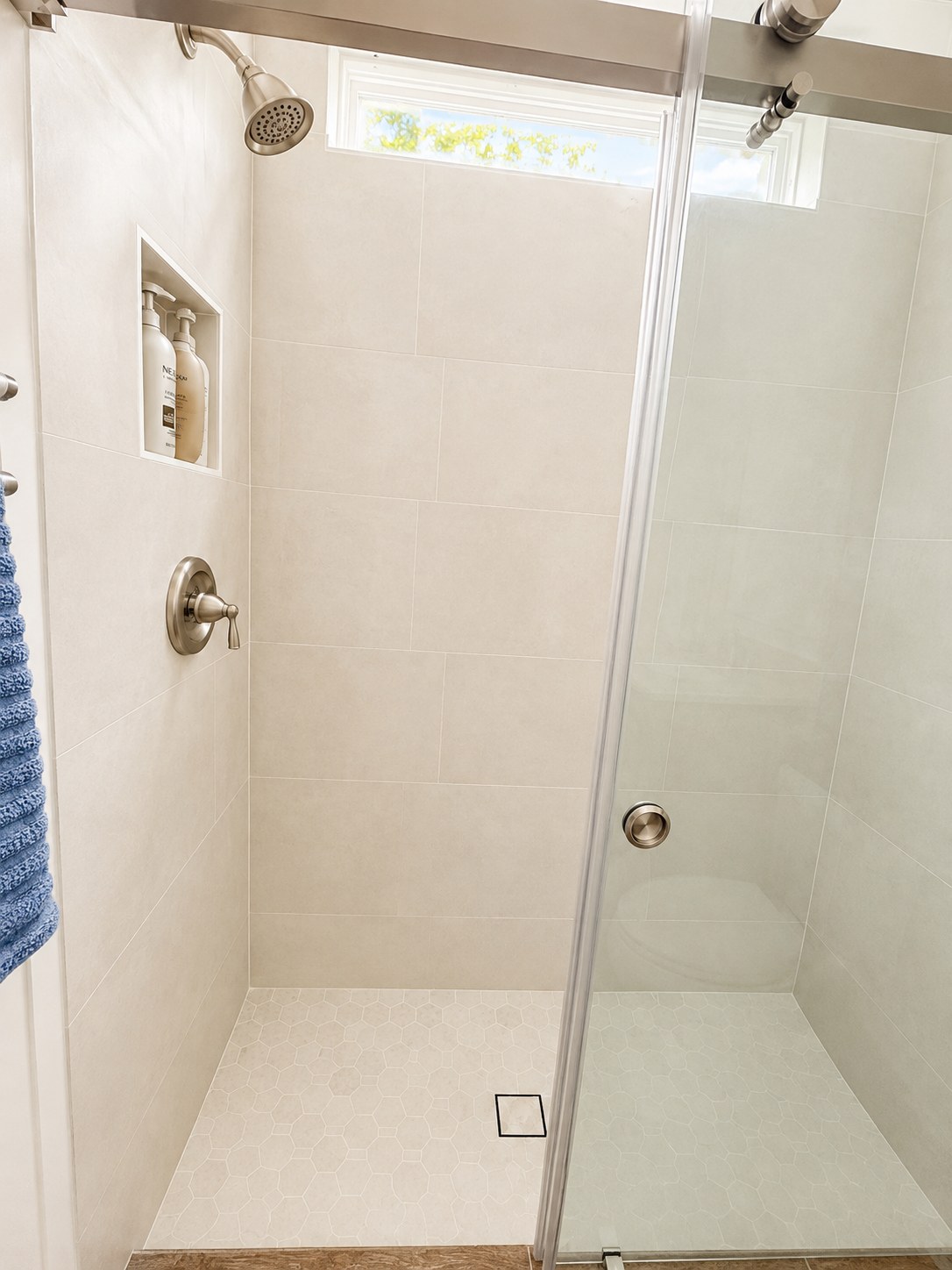 Finished walk-in shower with frameless glass door and hexagon tile floor