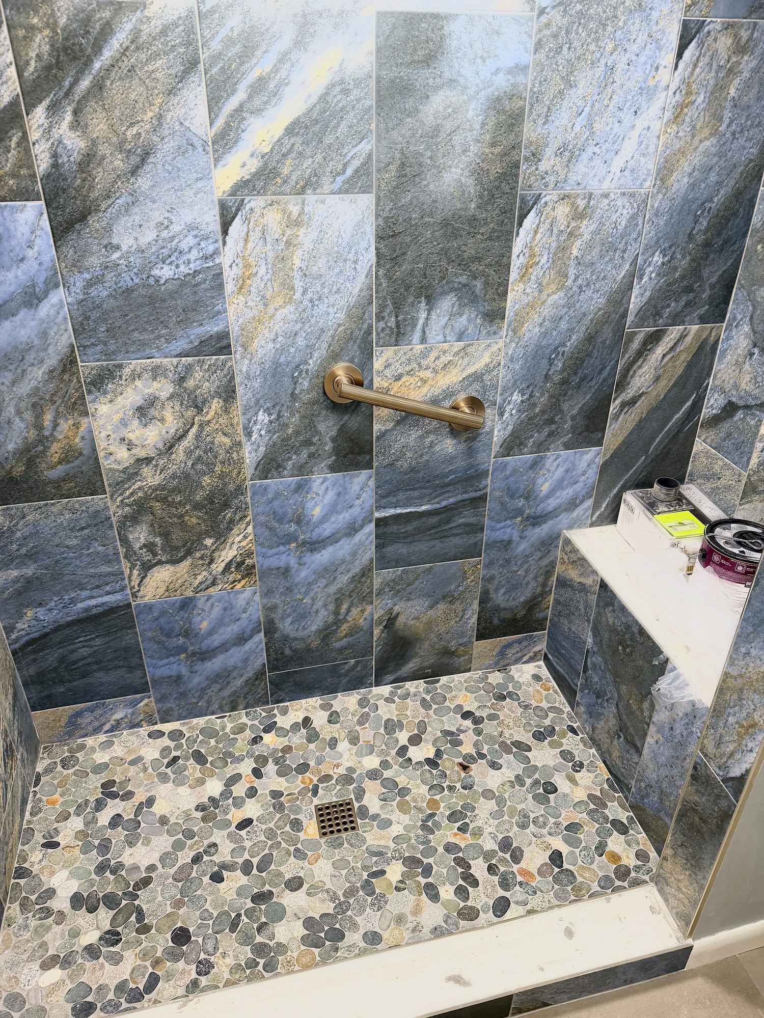 Finished shower with slate-look tile and a pebble floor