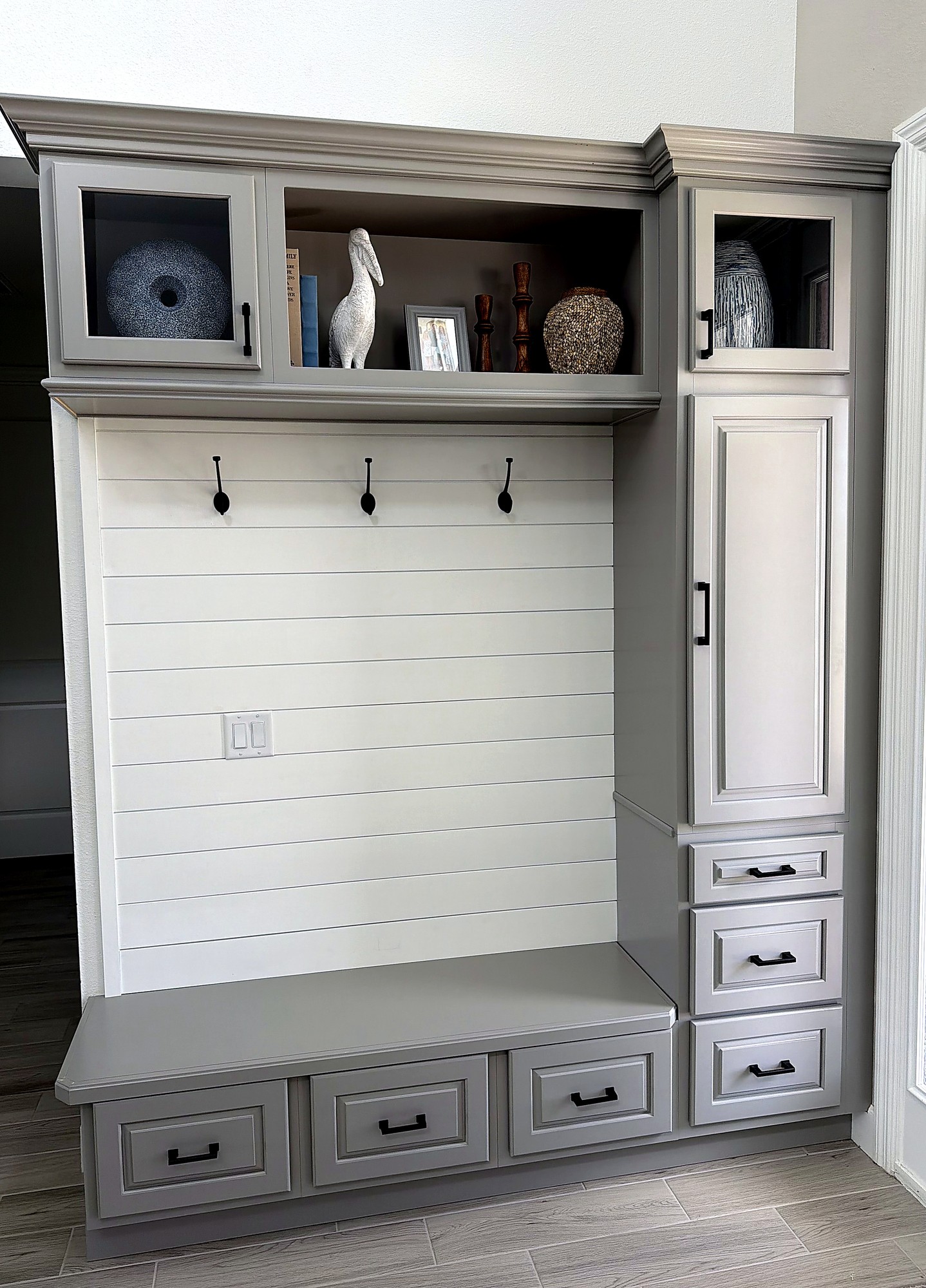 Custom mudroom drop zone with coat hooks, shiplap, and storage cabinetry