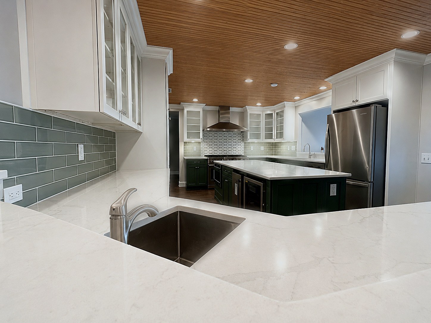 Kitchen remodel sink view with quartz counters and sage green tile backsplash