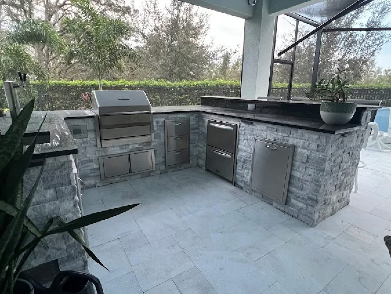 Stone veneer outdoor kitchen with black quartz counters, poolside