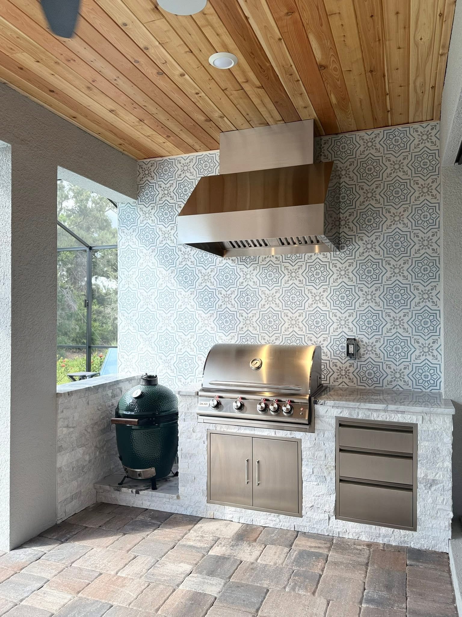 Finished outdoor kitchen with tiled backsplash and built-in grill