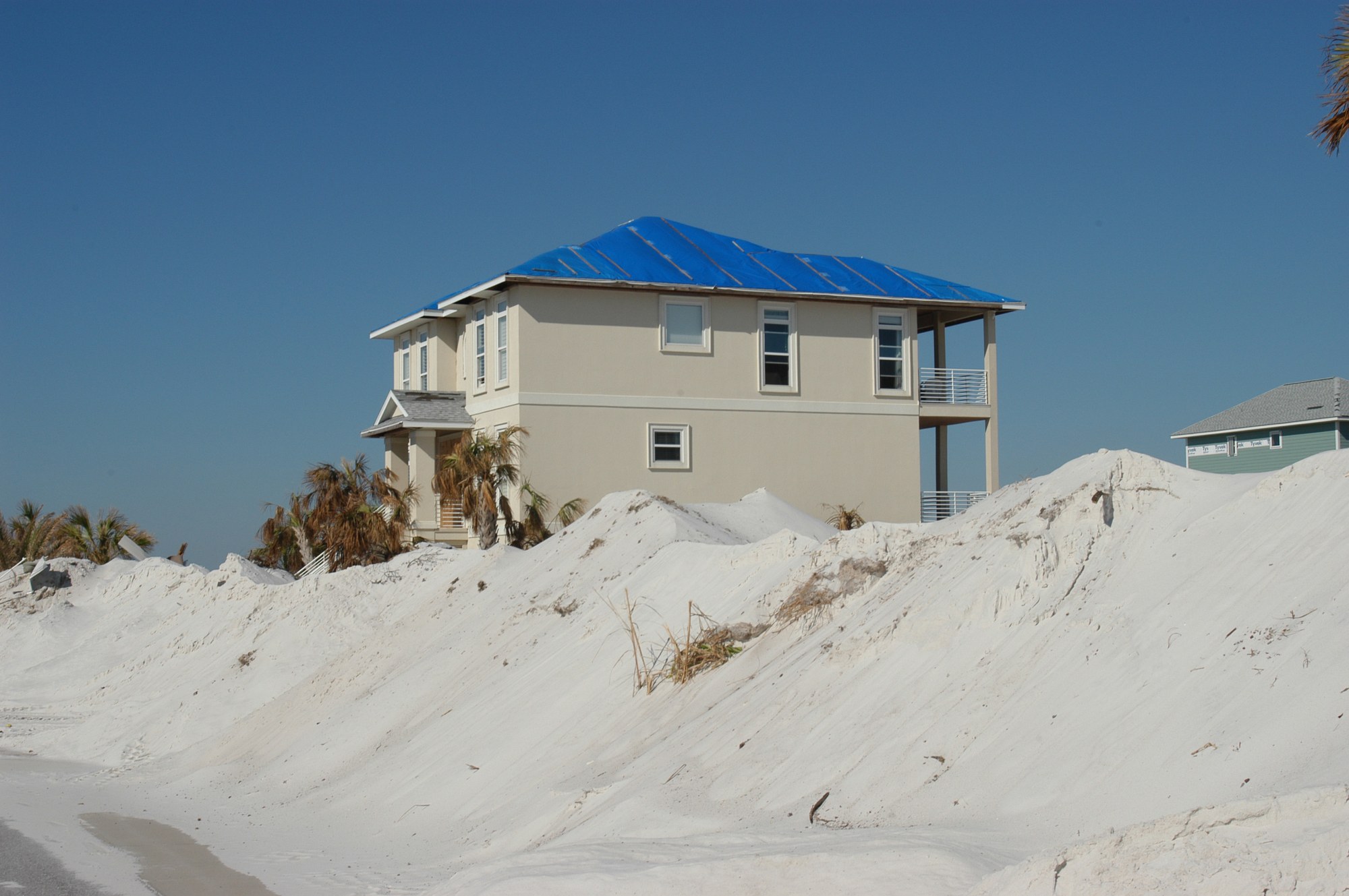 A Florida home with a temporary blue tarp roof after hurricane damage